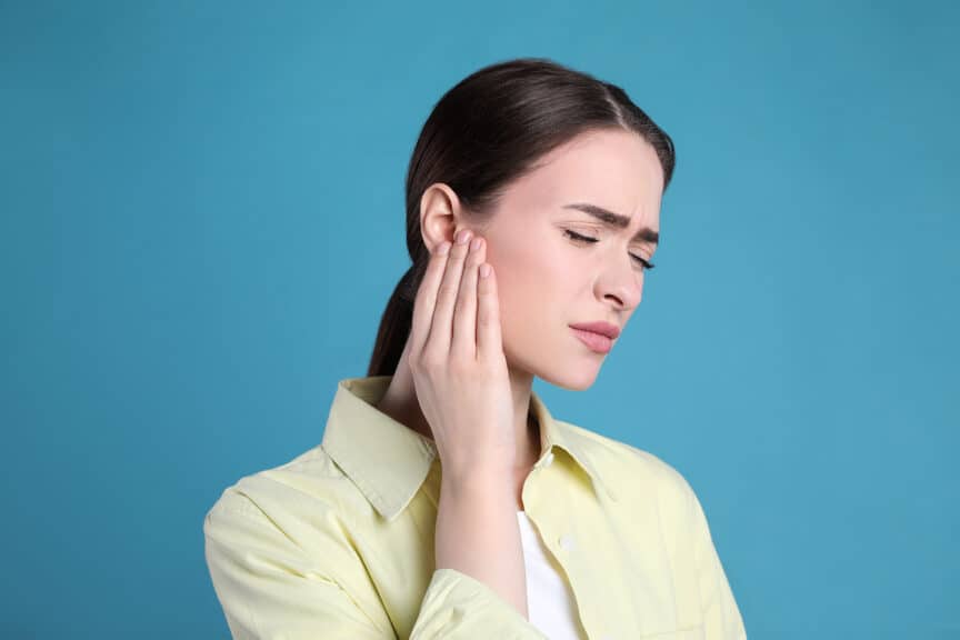 woman holding ear in discomfort